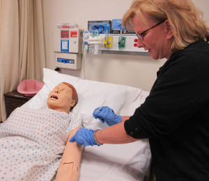 PRACTICE MAKES PERFECT: Above, Noella Erichson practices sticking a syringe into a patient dummy. PHOTO BY KRISTEN RIEDEL