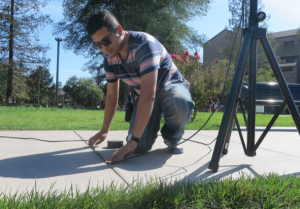 MORE THAN COMPUTERS: Diego Nunez, top, with Thomas Yee, bottom, set up sound equipment for the President’s Pledge Signing with the National Association for Community College Entrepreneur- ship in the Delta College Plaza on Oct. 7. PHOTOS BY KRISTEN RIEDEL