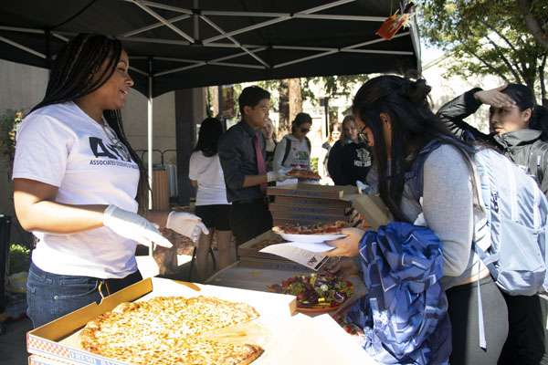 ASDC Director Shayla Walker serves students pizza from Costco at Autumn Fest.
