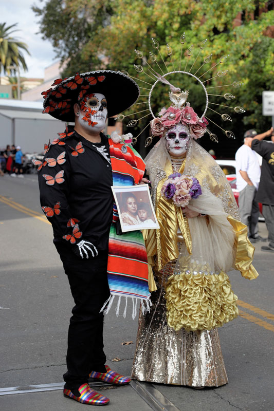 A couple stops to pose while they walk the streets during the Mexican Heritage Centers’ fourth annual Dia de los Muertos (Day of the Dead) community street fiesta on Saturday