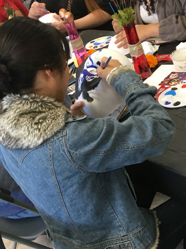 Guests at the Dia Del los Muertos painting their masks at the workshop tables. PHOTO BY JOHN NGUYEN