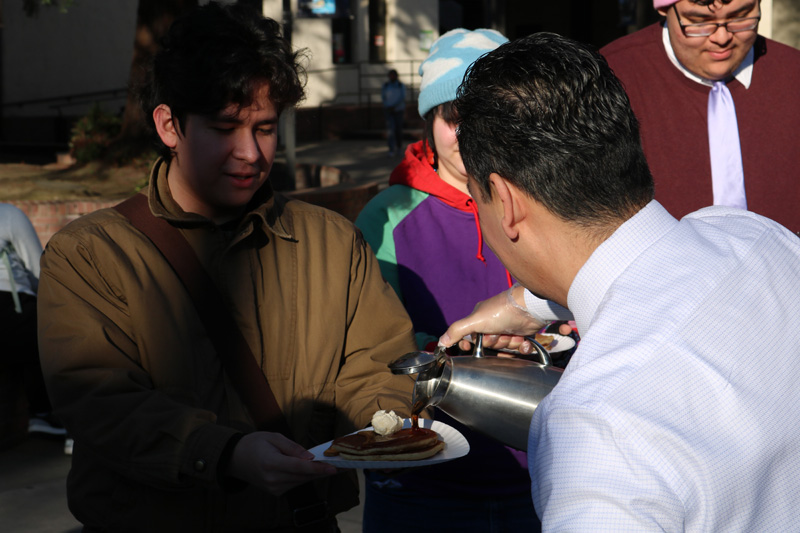 Vice President of Administrative Services Augustine Chavez serves syrup to Delta student Jennifer Mondragon at Pancakes with the President on Jan. 13, 2025.