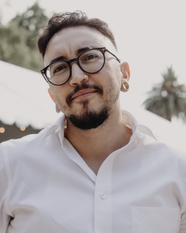 Professional headshot of a man with glasses, facial hair, and a white button-down shirt photographed outdoors.