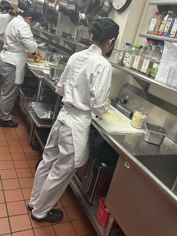 Kim "May" Chanbormey is cutting up some cauliflower (photo taken by Jacob S Manglinong of MCOM 10)